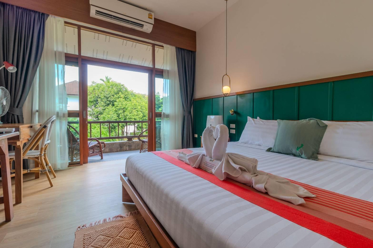 Guest room with a wooden balcony overlooking the green garden at Auangkham Resort Lampang