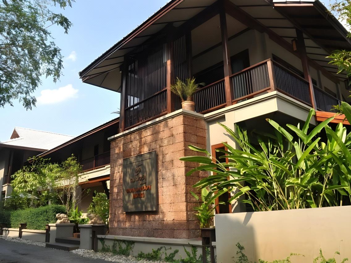 อาคารเรือนไม้ล้านนาและป้ายศิลาแลงของ At Lampoon Hotel กลางวัน