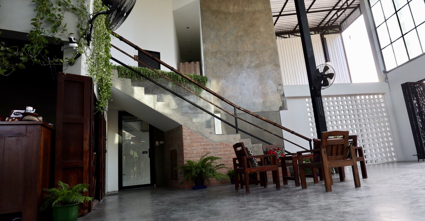 Double-height lobby with polished concrete floor and steel staircase at Norn Lamphun