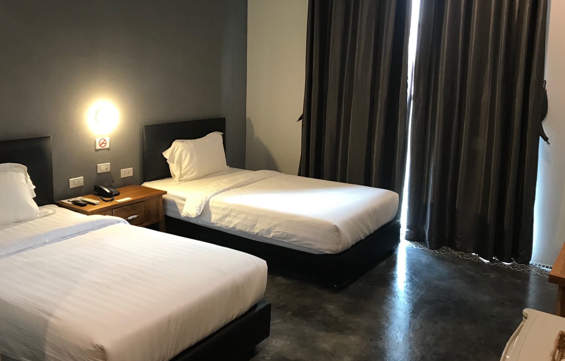 Twin room with raw concrete floor and dark grey walls