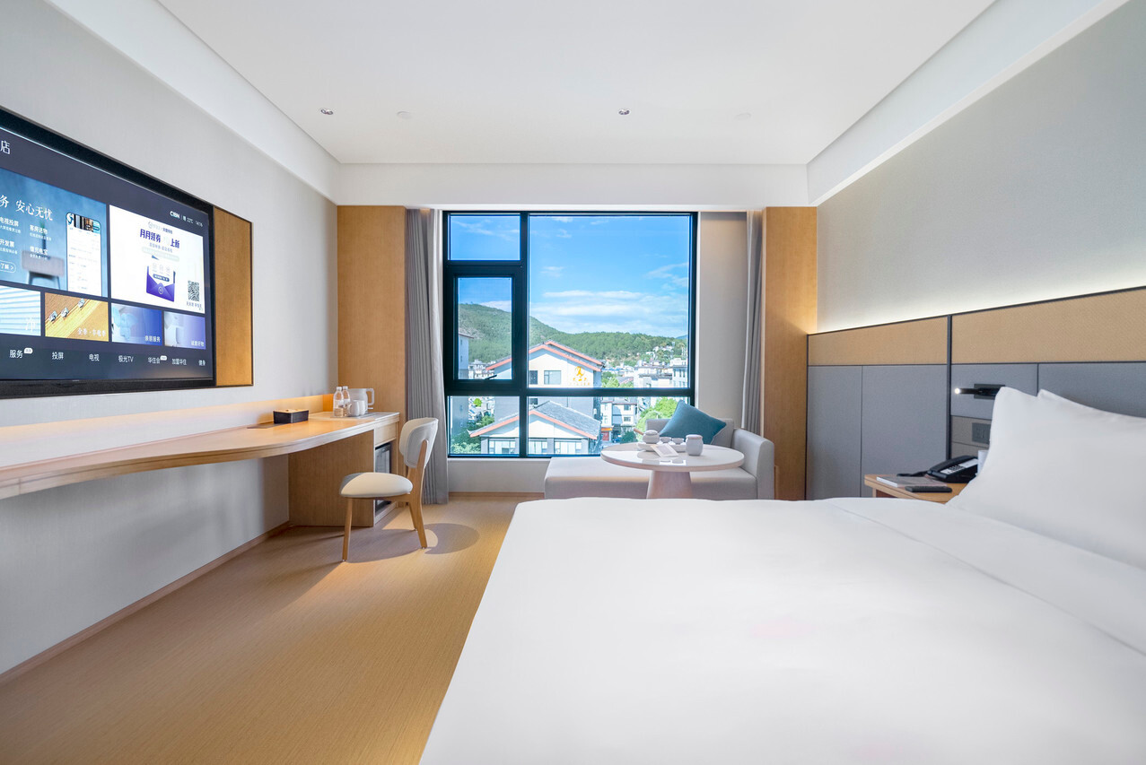 ห้องพักเตียงคิงของ JI Hotel Lijiang Ancient Town (全季酒店丽江古城店) โทนไม้อบอุ่น หน้าต่างวิวหลังคาเมืองเก่าและภูเขา