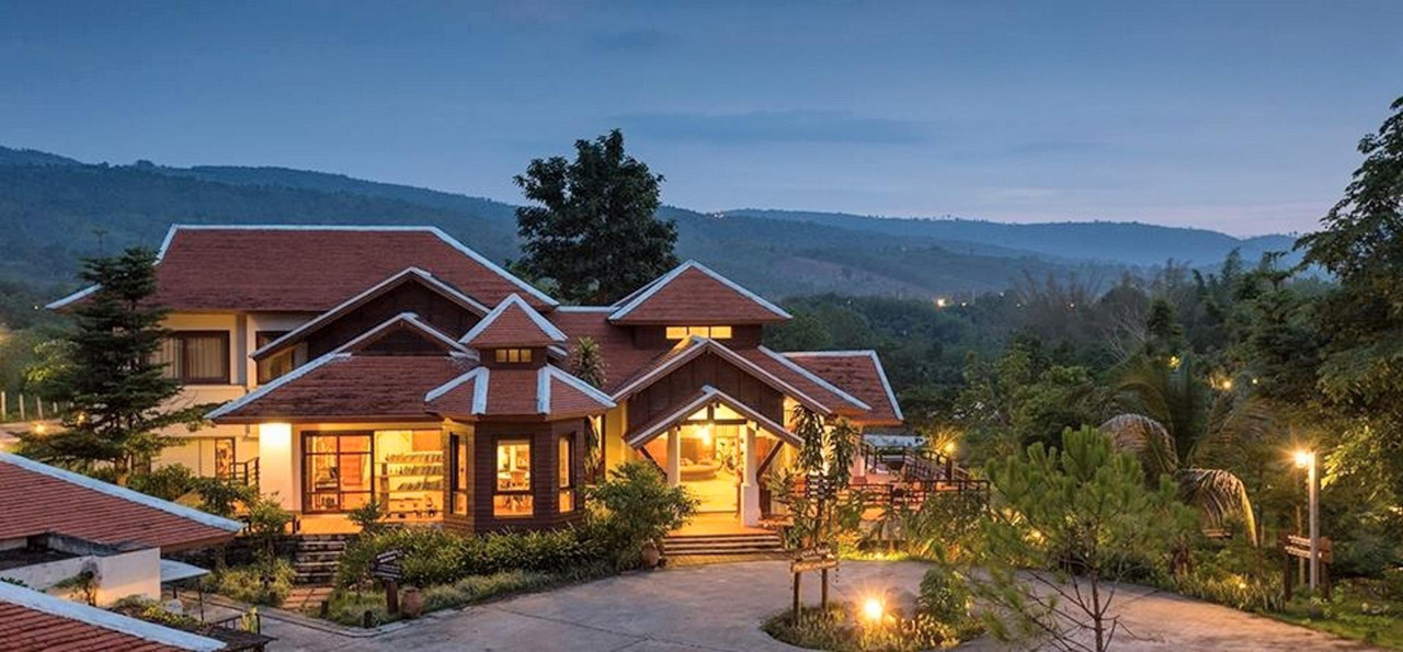 Timber reception building of Phunacome Resort at dusk with mountains behind
