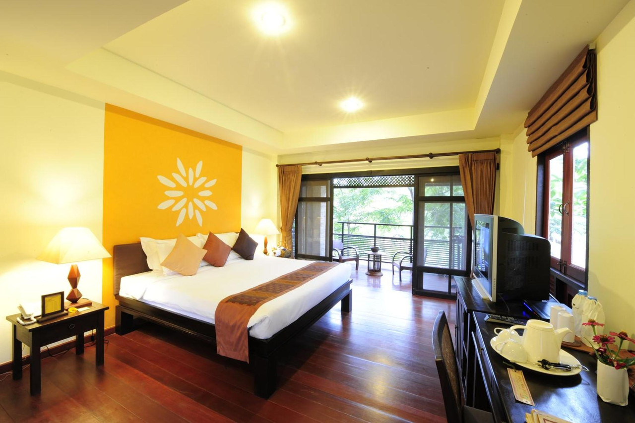 Guest room with wooden floor, flower-motif wall and a balcony onto greenery