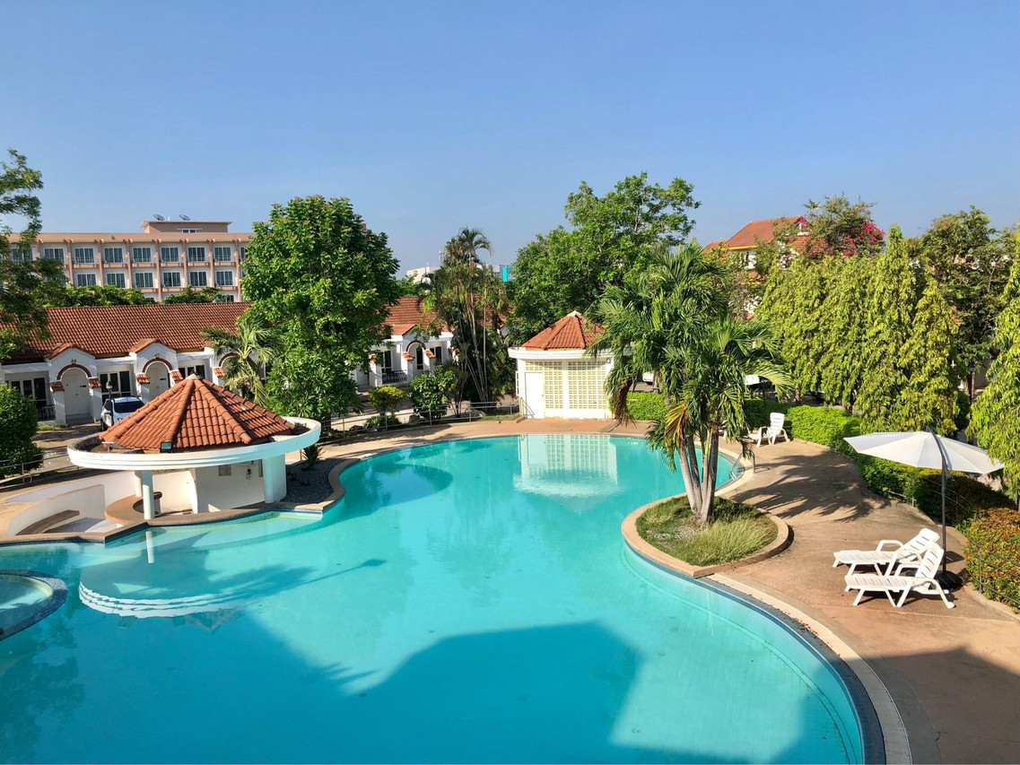 Curved outdoor pool with a poolside sala and garden at Lopburi Inn Resort