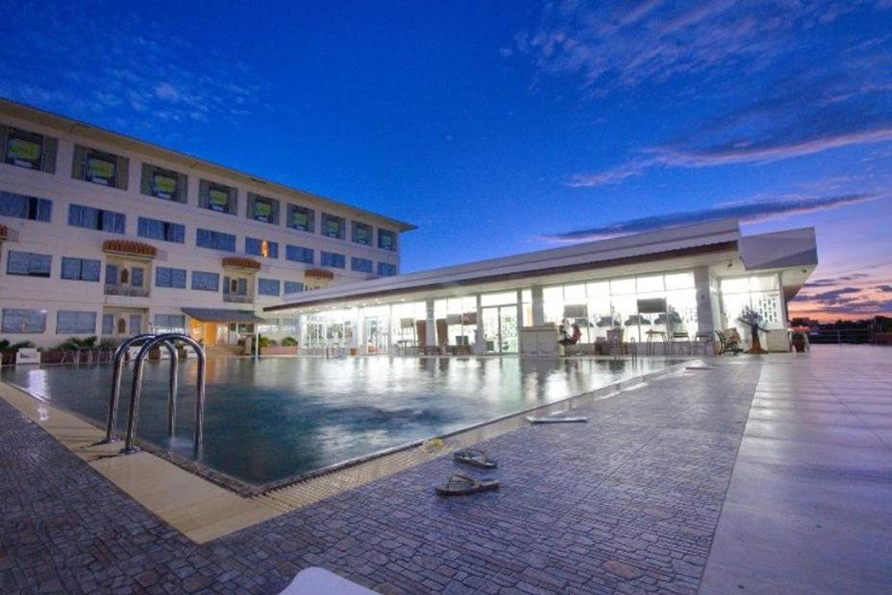 Outdoor pool at Taksila Hotel at dusk with a room wing behind it