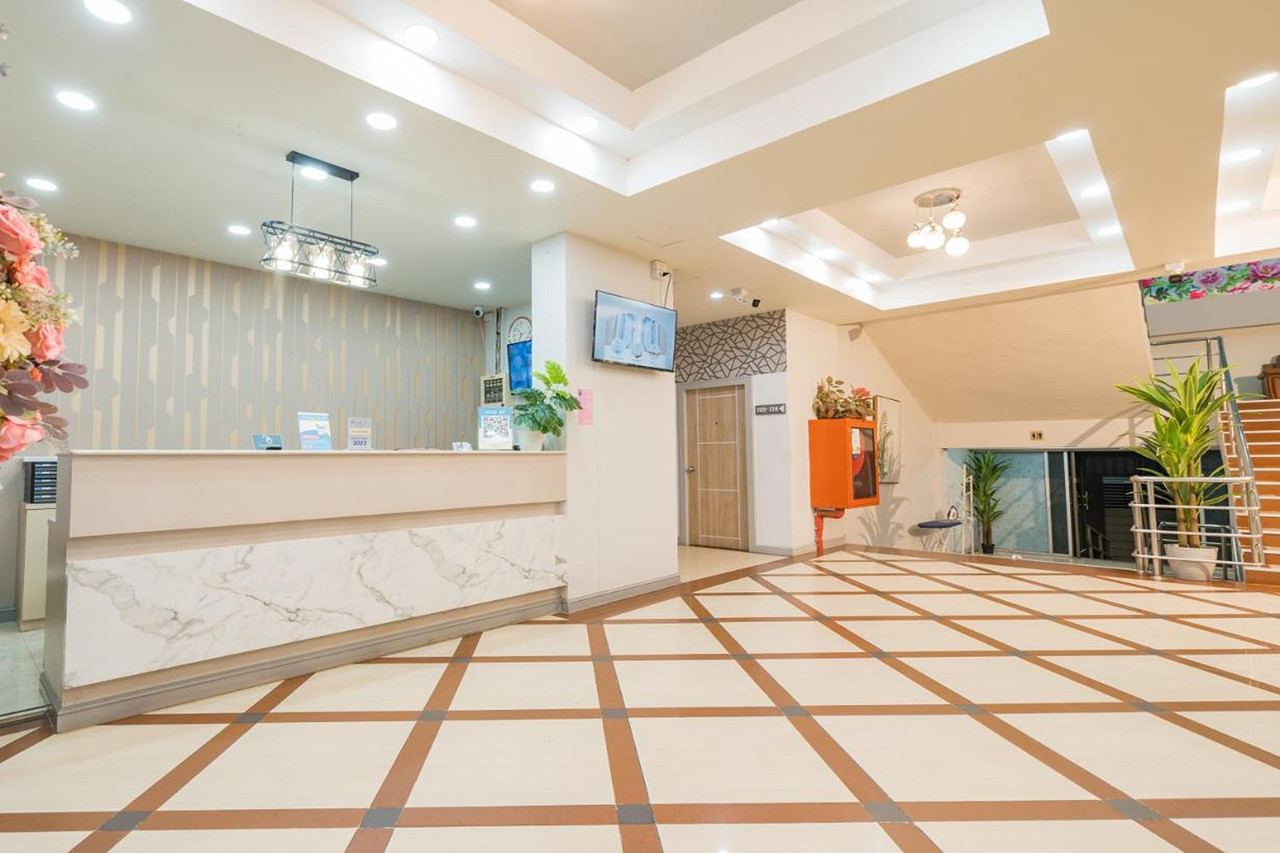Marble reception desk at Top Inn Hotel with cream-and-brown lattice tile floor