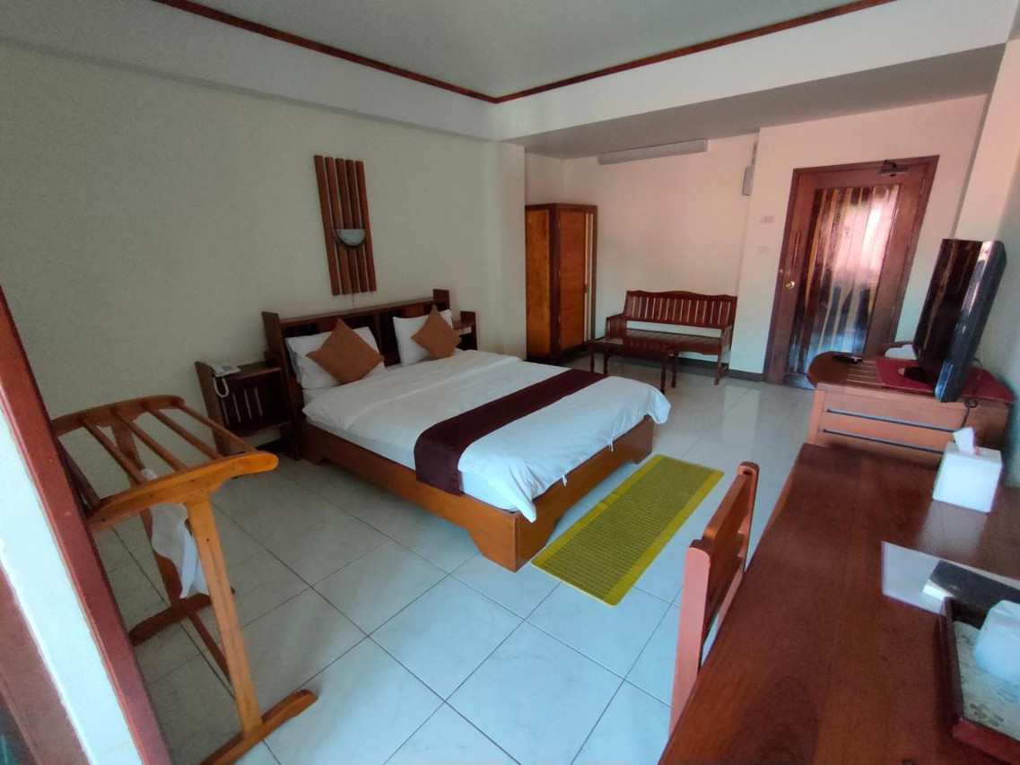 Guest room with large bed and solid teak furniture at Riverfront Hotel Mukdahan