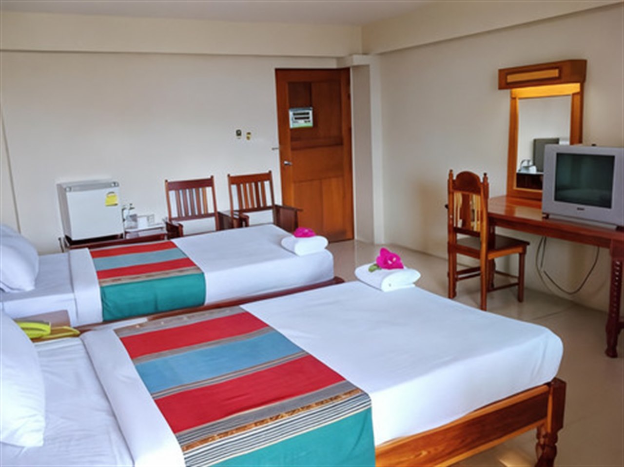 Twin room at Submukda Grand Hotel with bright woven bed runners, a fridge and a wooden dressing table