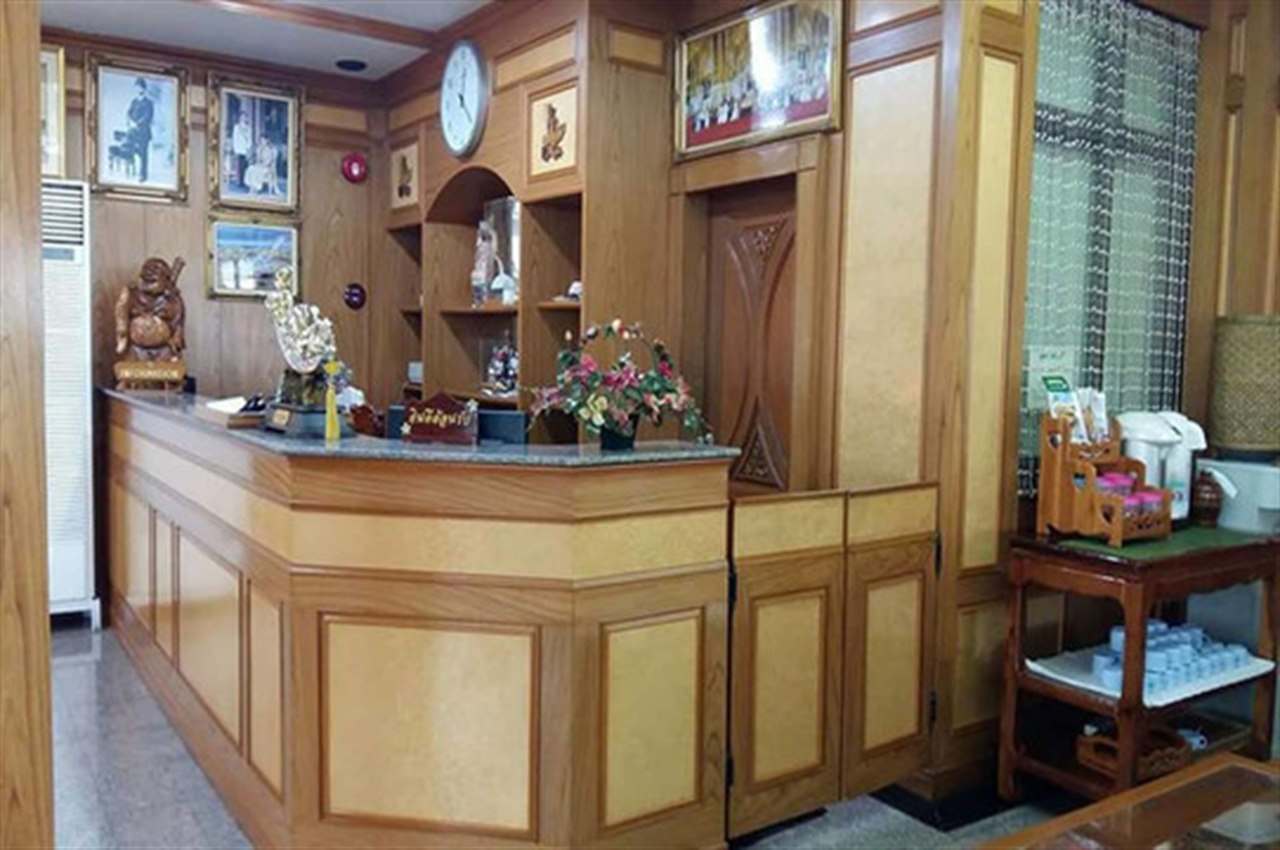 Wooden reception counter at Submukda Grand Hotel with royal portraits and Thai decorations
