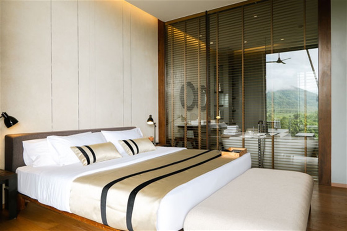 Suite with a large bed and a glass wall framing the mountains, timber-screened bathroom