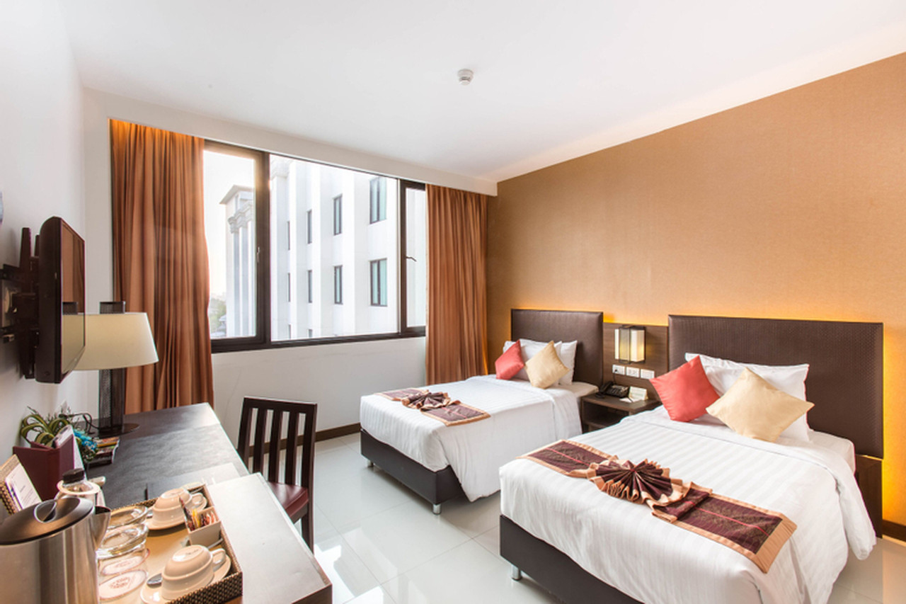 ห้อง Deluxe ที่ Mida Grande Dhavaravati นครปฐม เตียงคู่โทนน้ำตาลอุ่น ผ้าทอทวารวดีบนเตียง