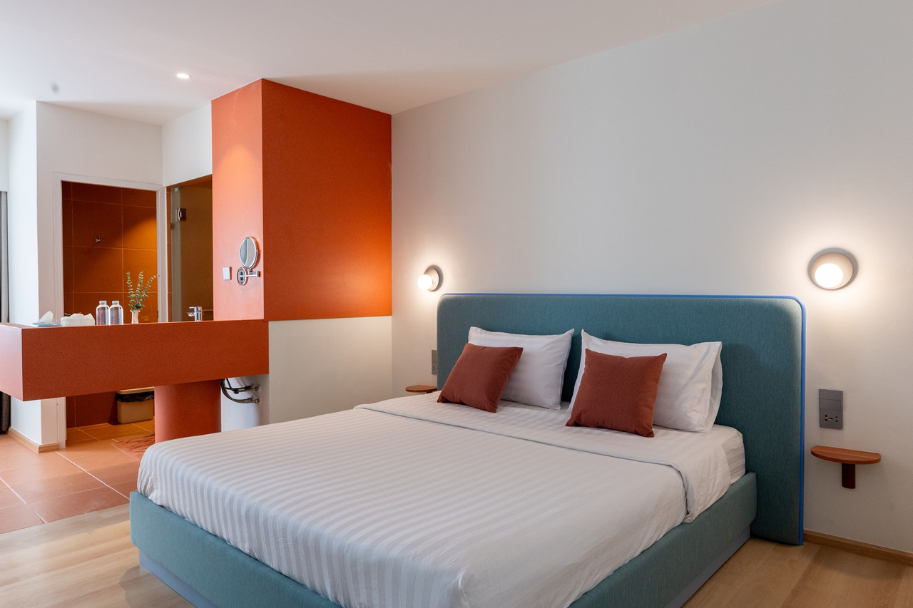 ห้องพัก 777Bliss Hometel เตียงหุ้มผ้าสีเขียวกับผนังสีส้ม ห้องน้ำแยกโซนเปียก-แห้ง