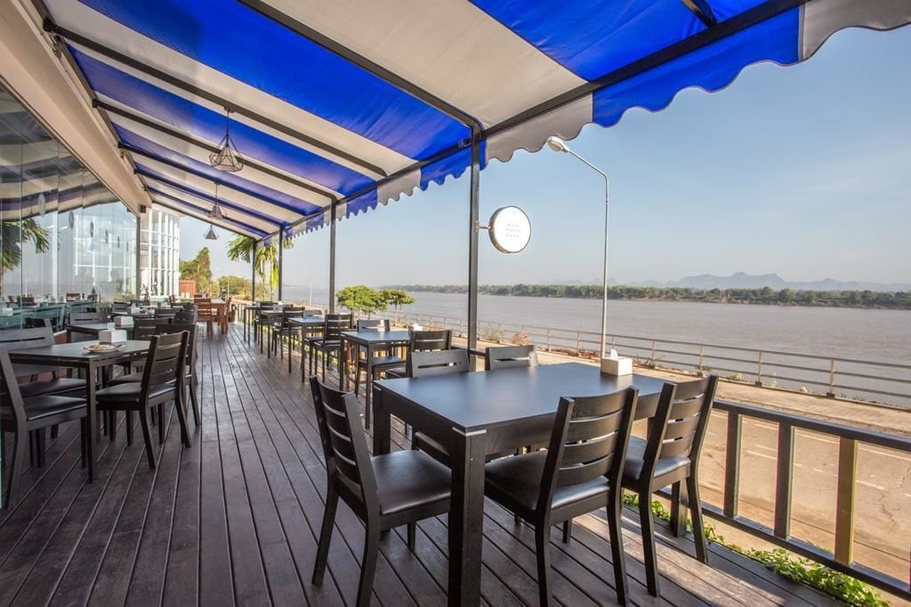 Riverside restaurant terrace at Blu Hotel overlooking the Mekong and the hills of Laos