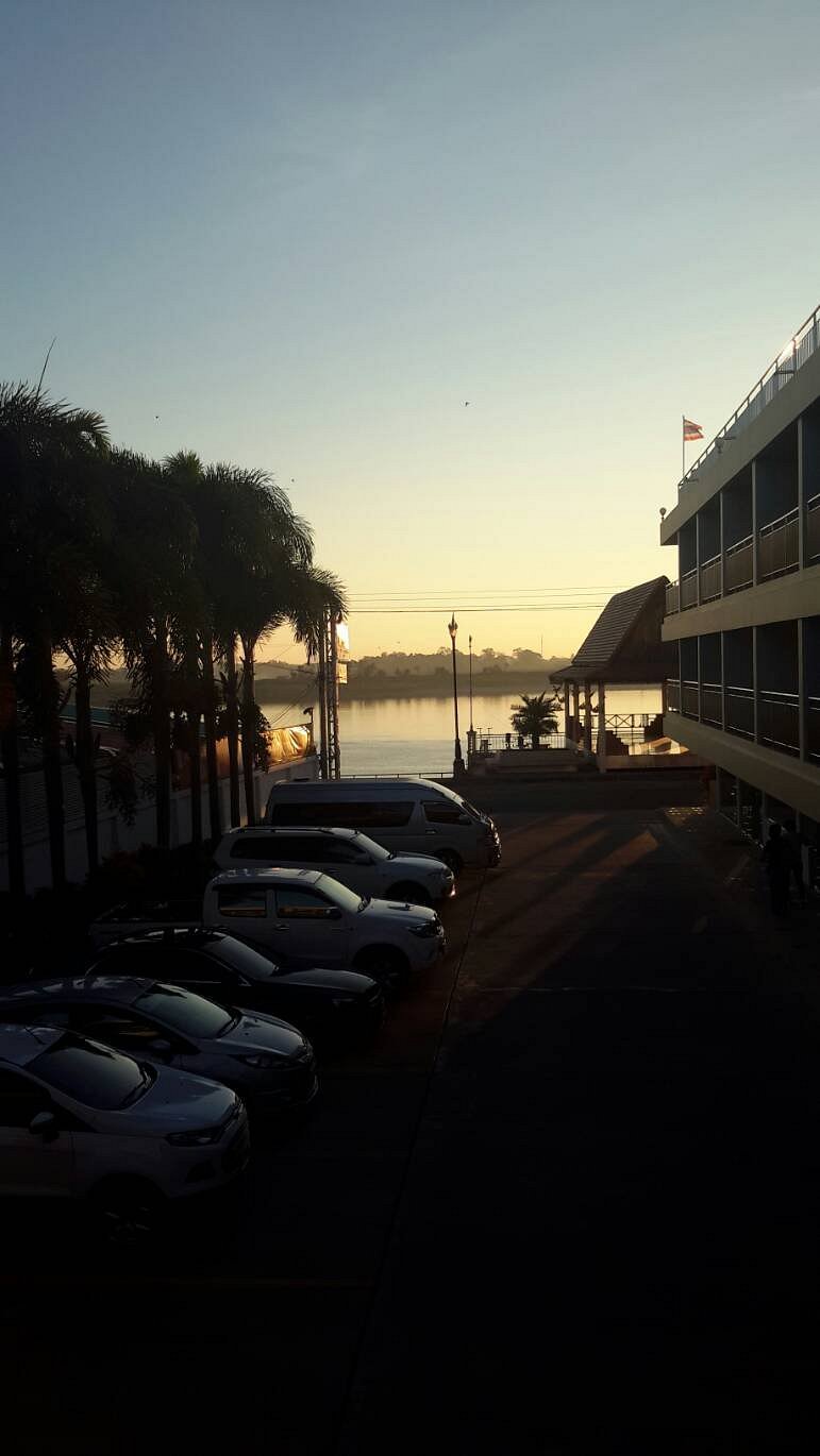 The hotel building at dawn, a riverside car park, and sunrise over the Mekong River