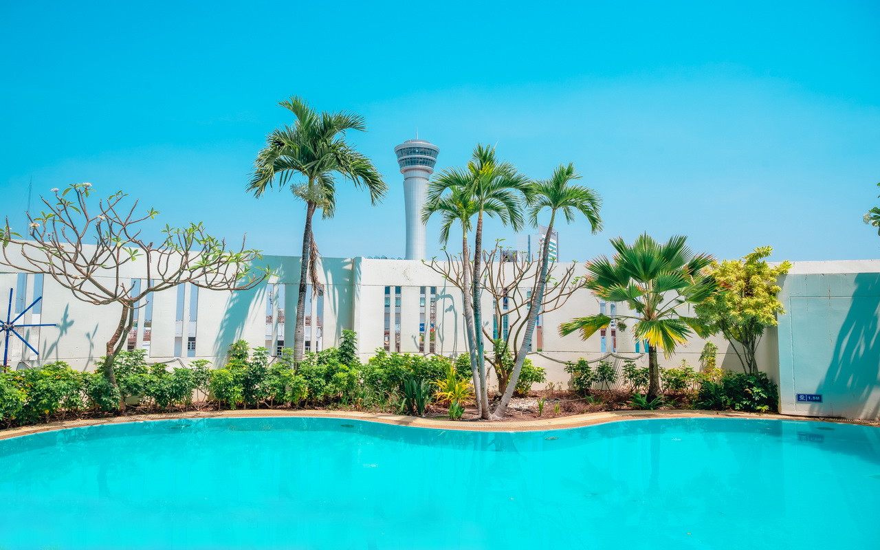 สระว่ายน้ำกลางแจ้งของ Fortune Hotel Korat มีต้นปาล์มและวิวหอคอย