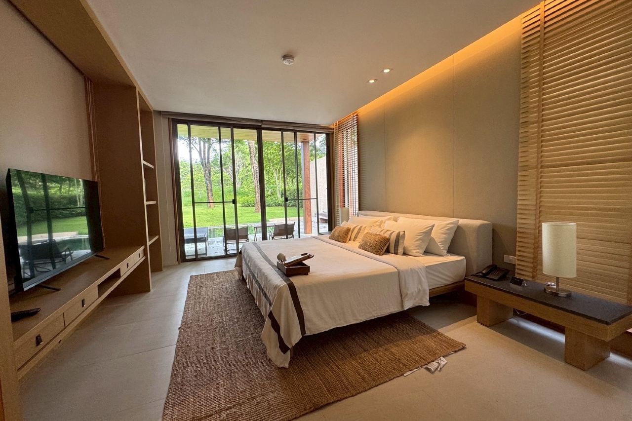 Villa interior in warm timber, opening to a wooden deck and forest garden