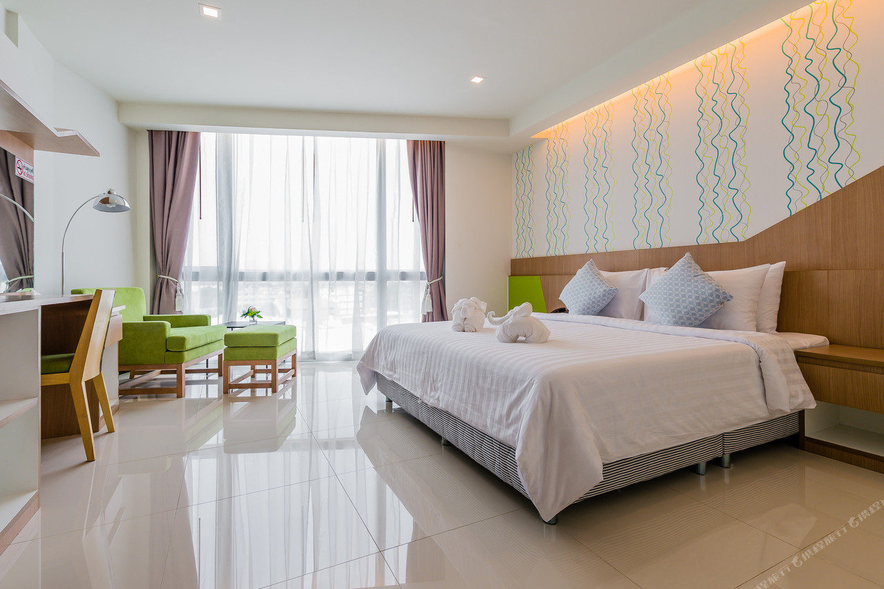 King room at 42C The Chic Hotel with white-tiled floor, green sofa and a large glass balcony