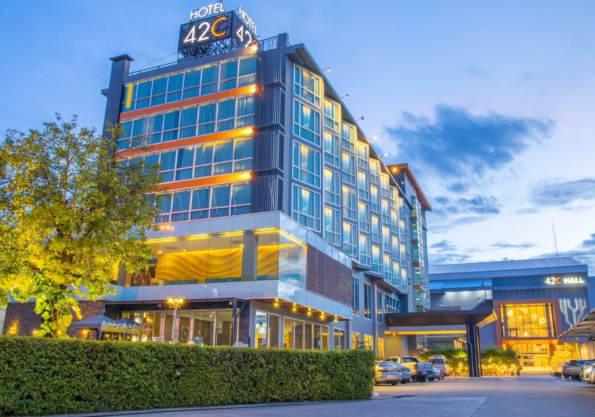 42C The Chic Hotel glass tower at dusk with the glowing rooftop sign and 42C Hall wing