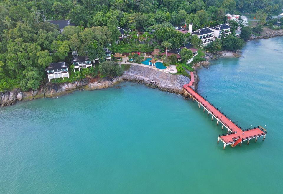 Aerial view of Racha Kiri Resort on a sea cliff with a red timber pier reaching into the bay