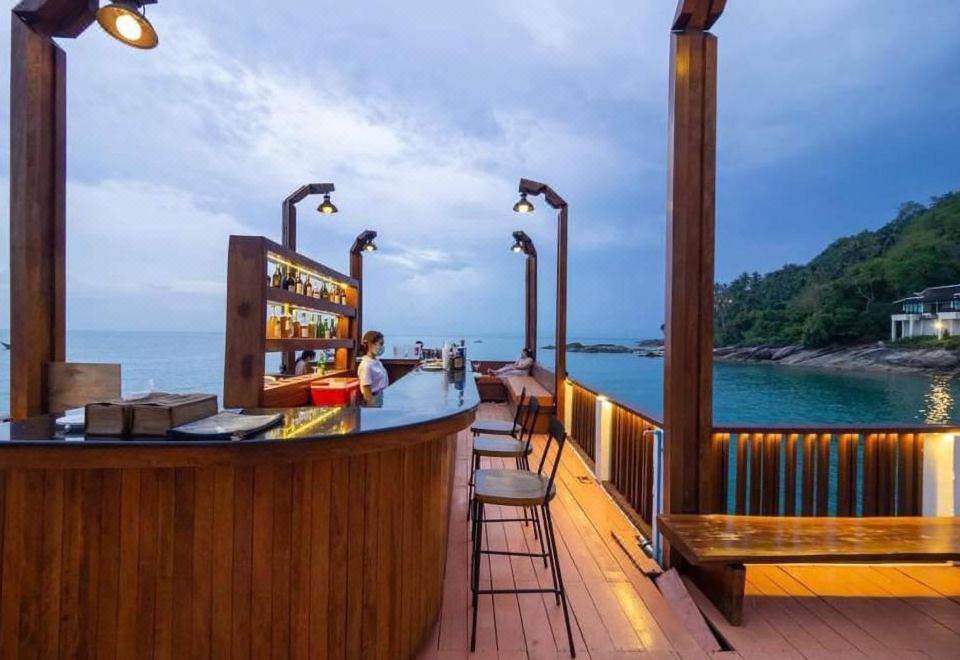 Open-air timber sea bar on a deck looking out over the water at dusk
