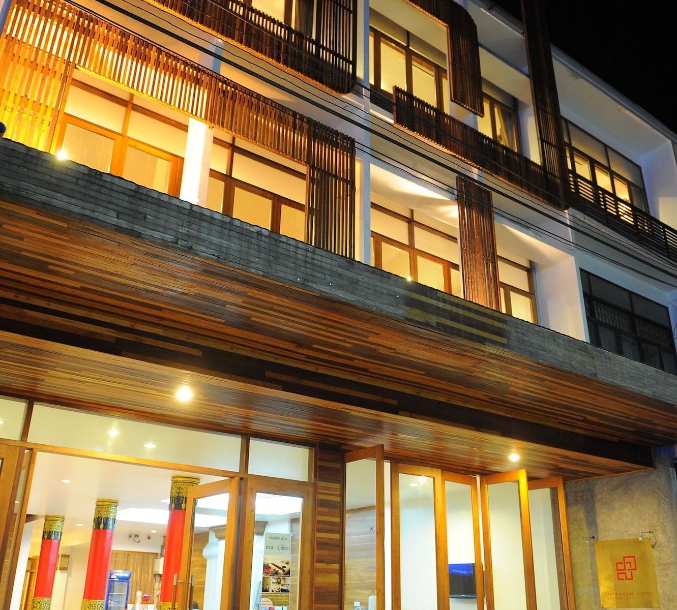 ตึกด้านนอก Sukkasem Hotel ยามค่ำ เห็นไม้สักทั้งหลัง
