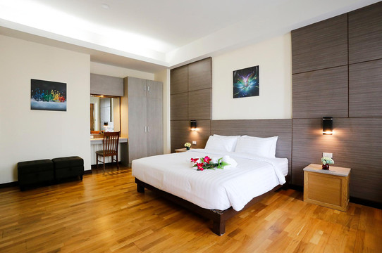 ห้องพัก Greenview Boutique Hotel เตียงใหญ่ พื้นไม้ ผนังไม้ มีดอกกล้วยไม้วางบนเตียง