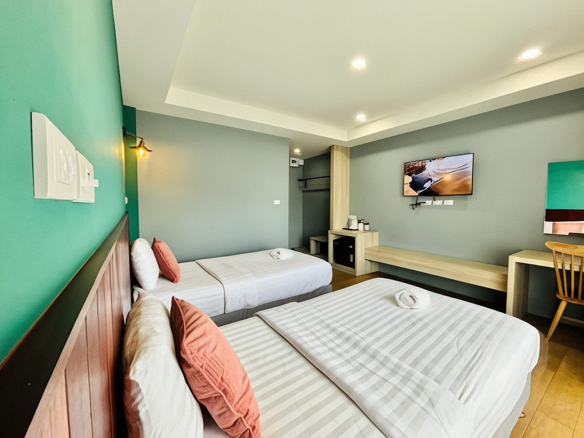 ห้องเตียงแฝดของ Pohnphansa Boutique Hotel ผนังสีเขียวเสจ หมอนสีอิฐ พื้นไม้ มีโต๊ะทำงาน