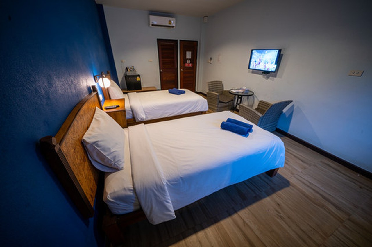 ห้องพักเตียงคู่ผนังโทนน้ำเงิน พื้นไม้ ทีวีจอแบน ที่ The Bed Kolok Resort