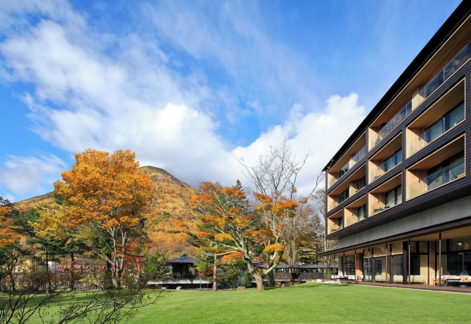 The Ritz-Carlton Nikko exterior with garden lawn, red torii gate and Mount Nantai in autumn