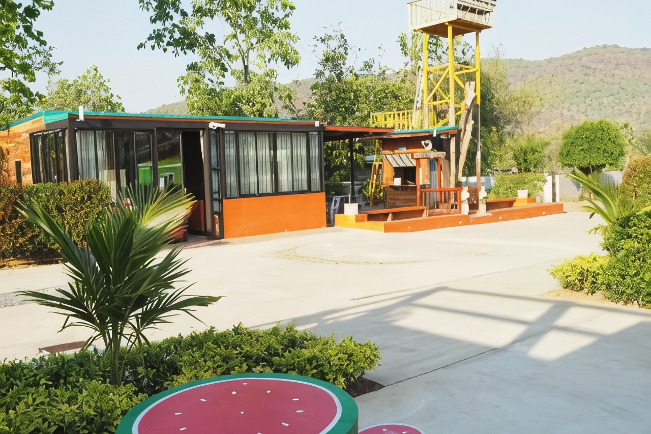 Central building and BBQ lawn in the garden, with a viewing tower and hills behind