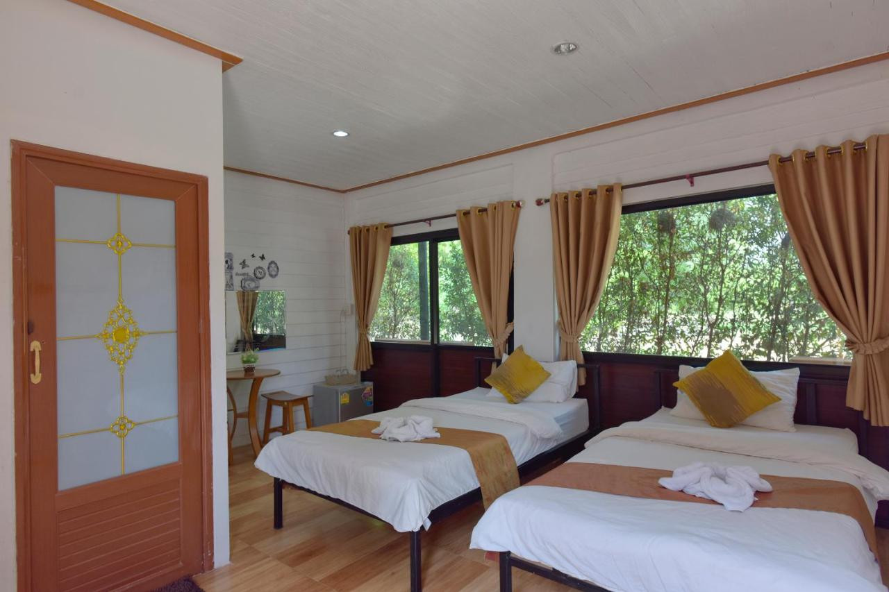 Teak-walled twin room with windows looking out onto green trees
