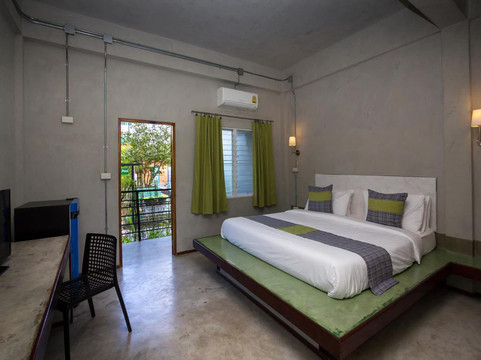Room at Nongbua Garden Ville with bare-concrete walls, a platform bed, green curtains and a balcony door opening to the garden