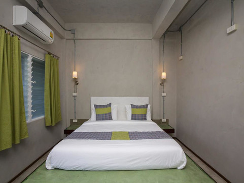Twin room with polished concrete walls, a platform bed, wall sconces and green curtains by the window