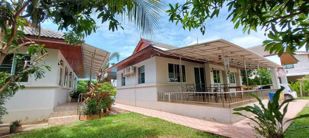 White Thai-roofed bungalows in the green garden of Nuch's Apple Guest House