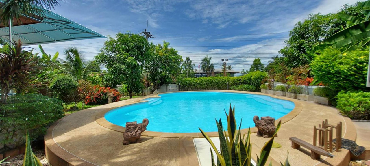 Outdoor apple-shaped swimming pool framed by tropical garden and elephant statues