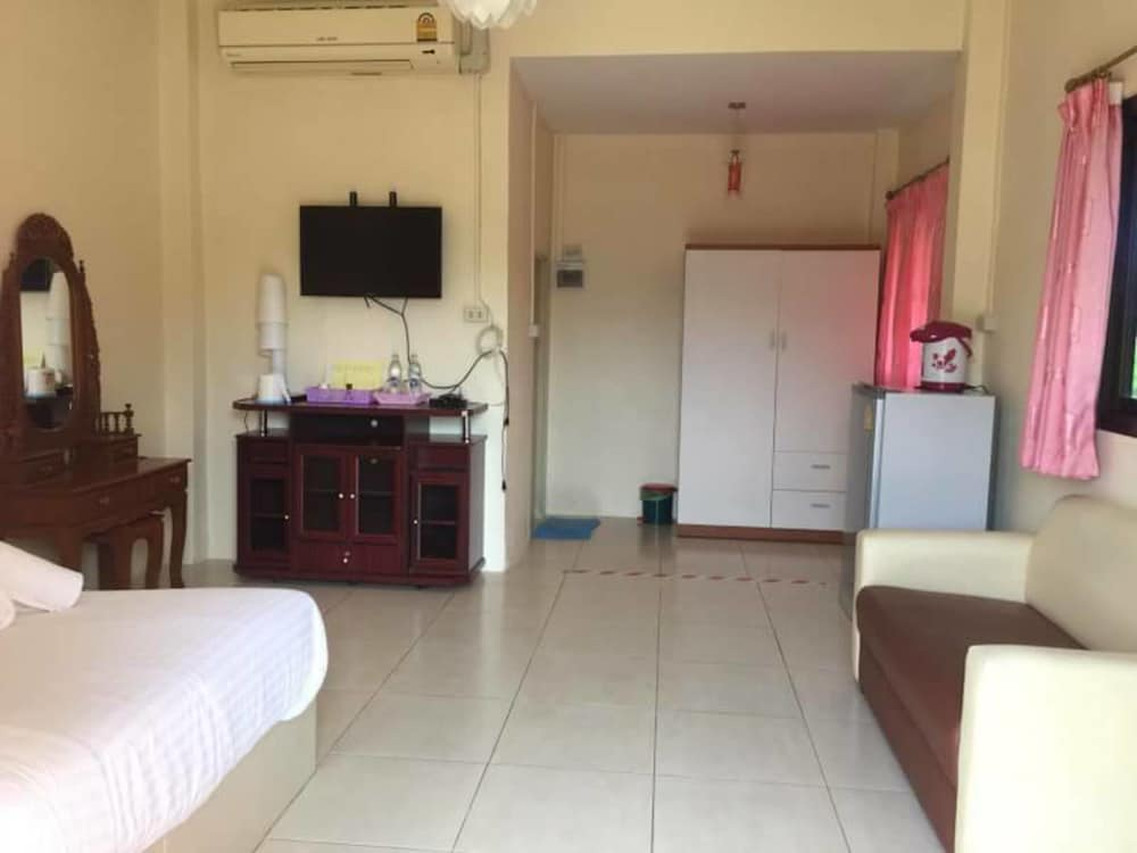 Room interior with bed, fridge, flat-screen TV and sofa