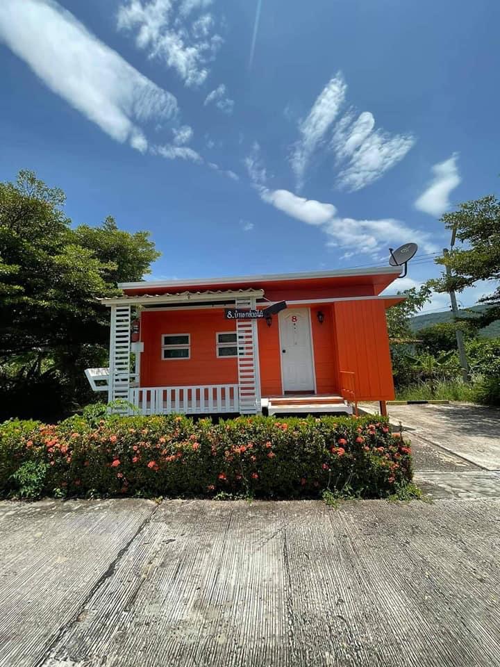 Orange bungalow with a private porch and flower beds out front