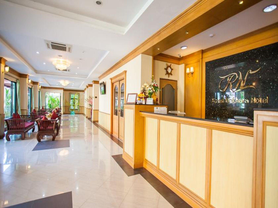 Lobby and reception desk at Royal Nakhara Hotel with the RN logo on the wall