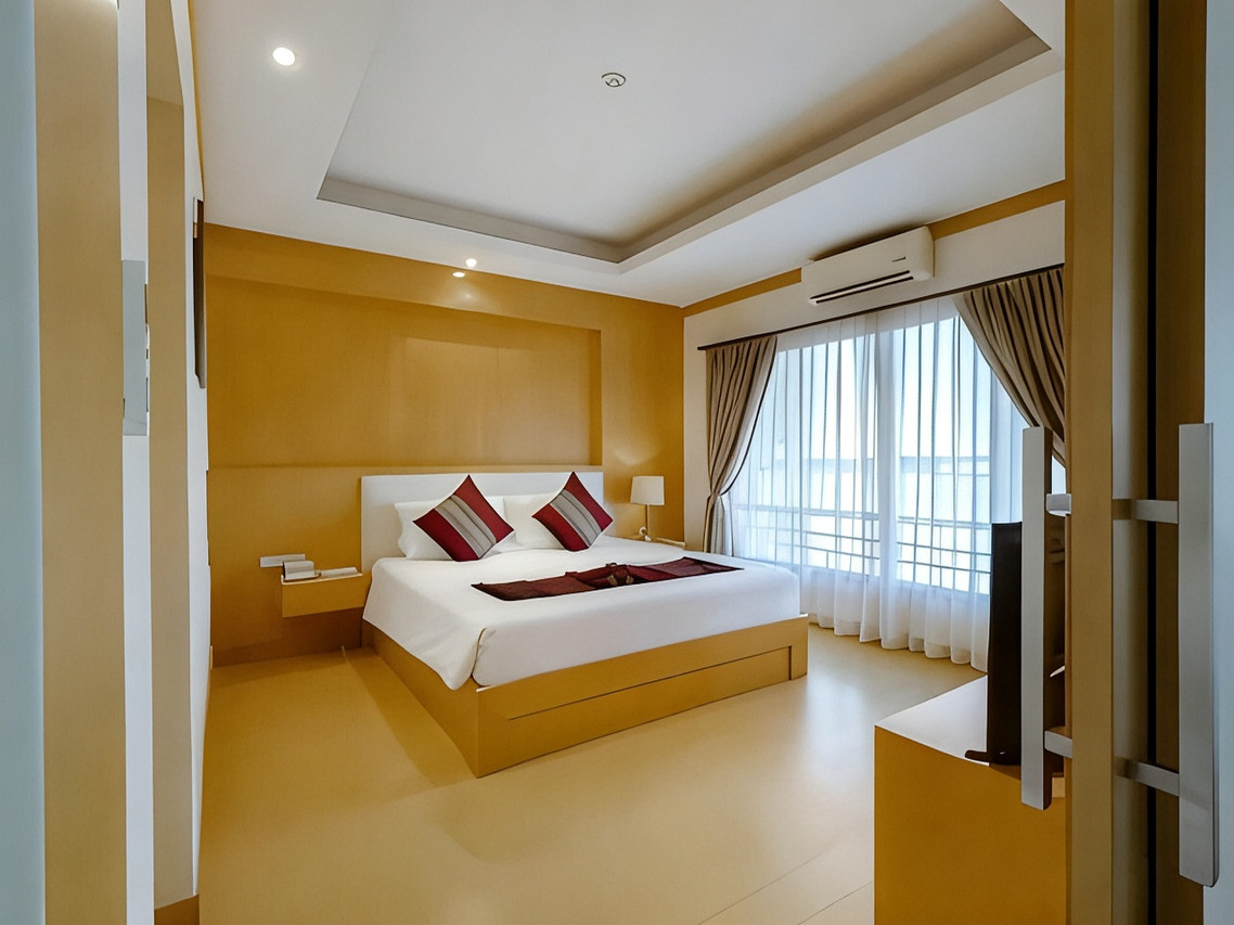 Guest room with a king bed, amber-toned walls, a balcony and sheer curtains