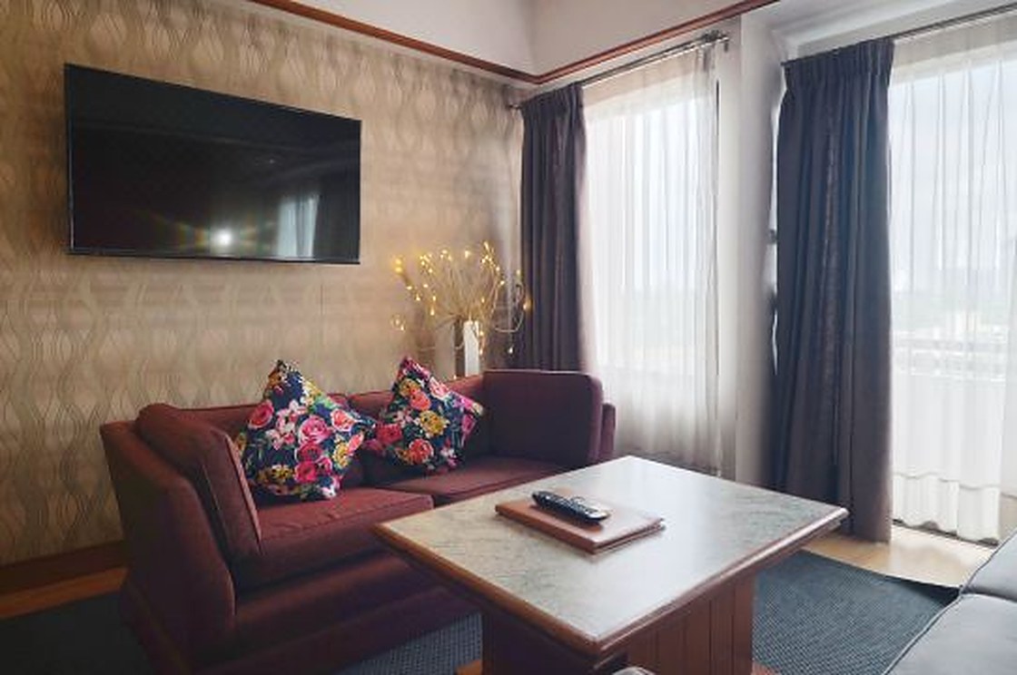 Junior Suite living area with a sofa, TV and balcony letting in daylight