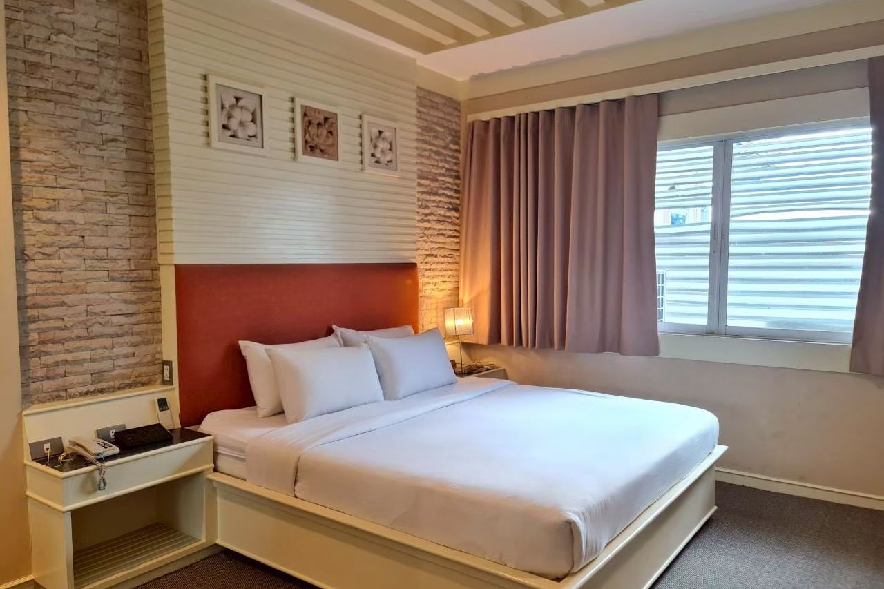 Double room with a faux-stone feature wall in warm tones at The Rich Hotel Nonthaburi