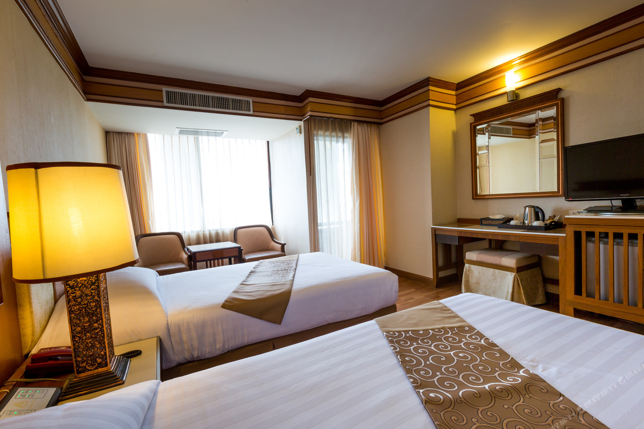Teak-trimmed guest room at Asia Airport Hotel with twin beds and dressing table