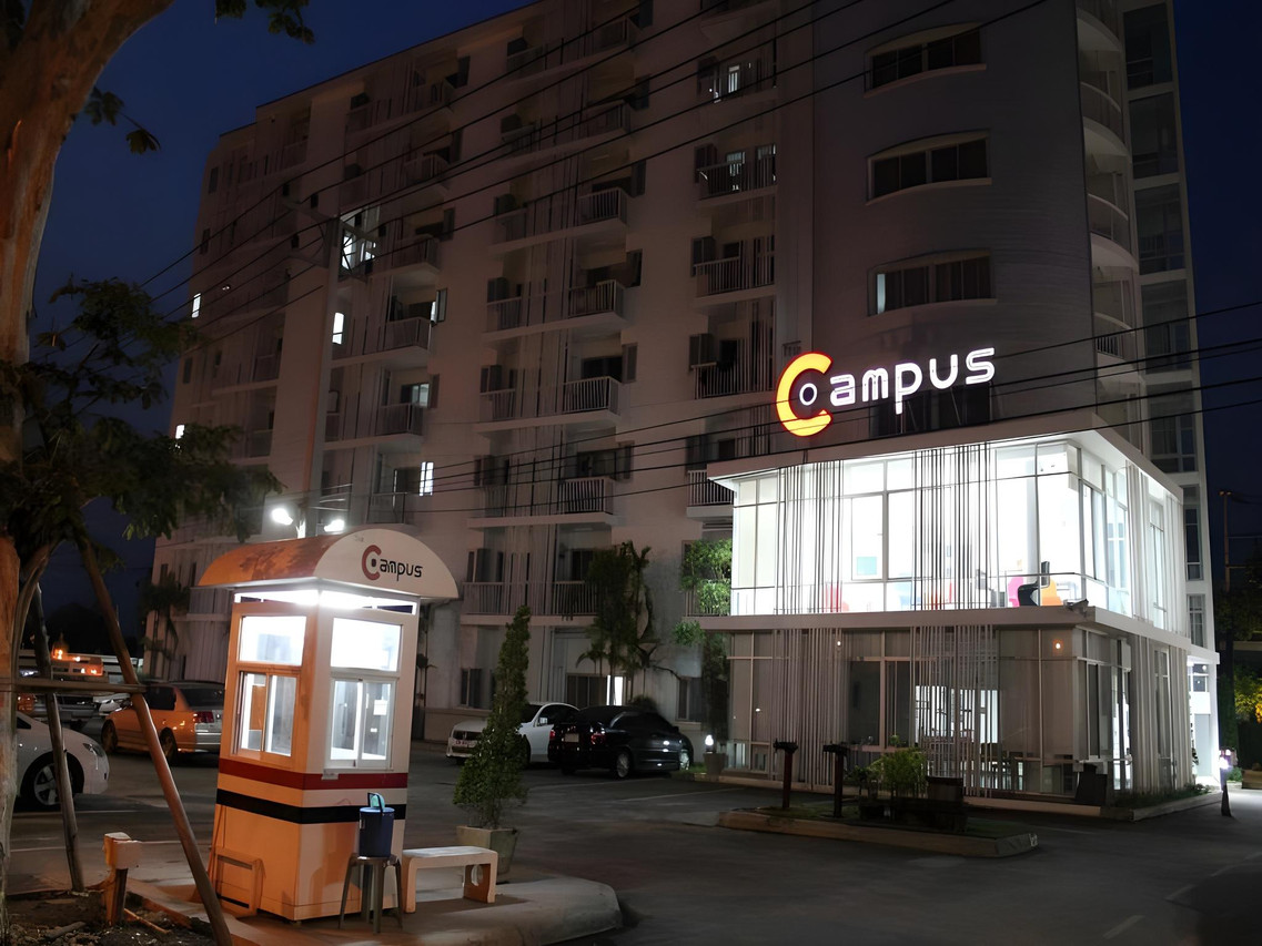 Lit Campus sign at night with the guard booth and glass café building