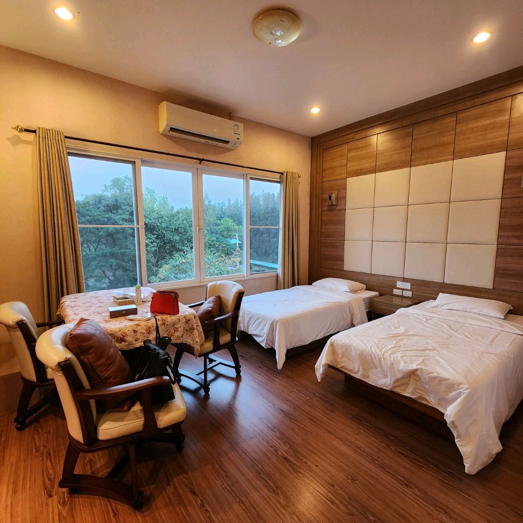 Twin-bed room with wood finishes and a large garden-view window at The Pine Resort