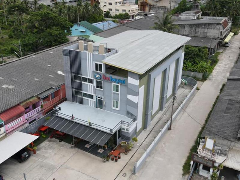 มุมสูงแสดงตึกสีเทาสี่ชั้นและย่านรอบ Chokphaiboon Apartment ปัตตานี