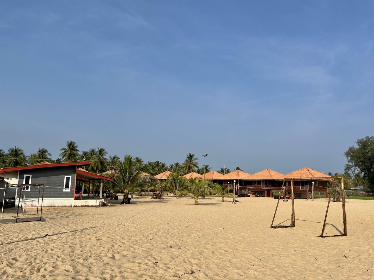Overview of D Tama Beach Resort, tile-roofed bungalows under coconut palms on Laem Pho beach