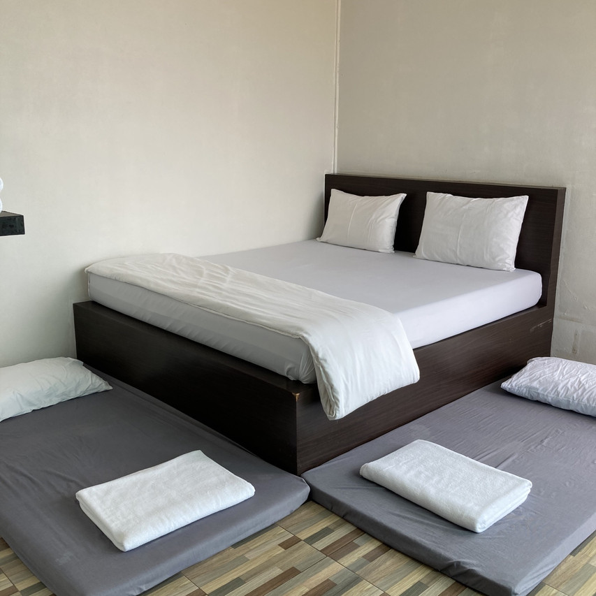 Simple room interior with a dark-wood bed and extra floor mattresses