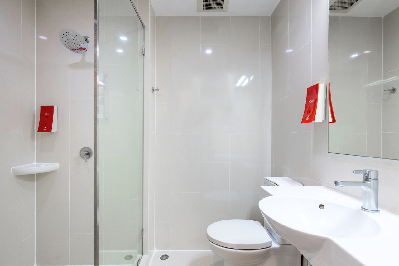 In-room bathroom with rain shower and clean light-tiled walls