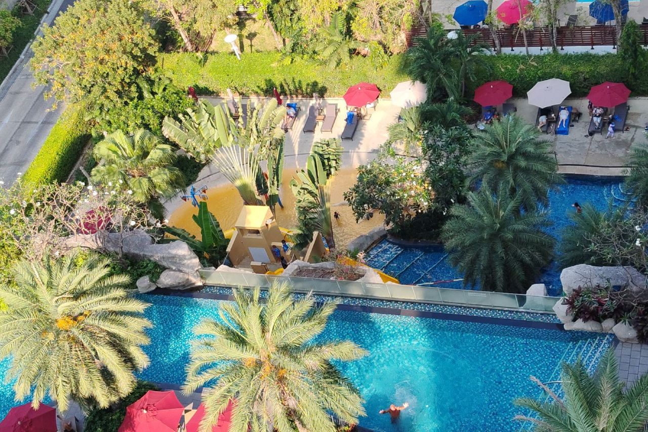 Aerial view of the resort pools and tropical garden with red umbrellas