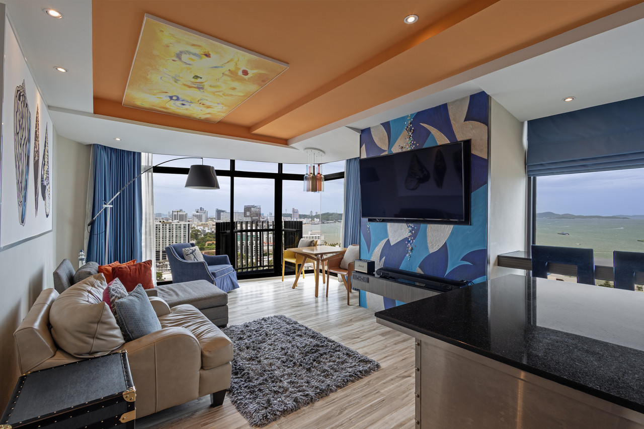 Design-led suite living area with a sofa and floor-to-ceiling windows facing Pattaya Bay